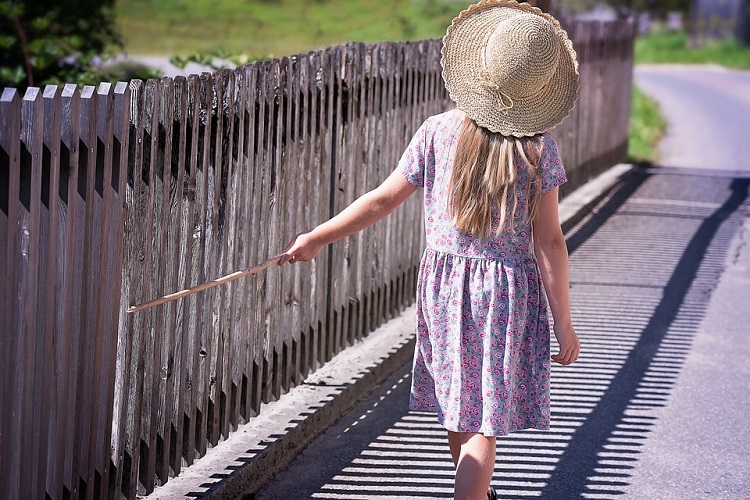 girl strolling along Wooden Fence