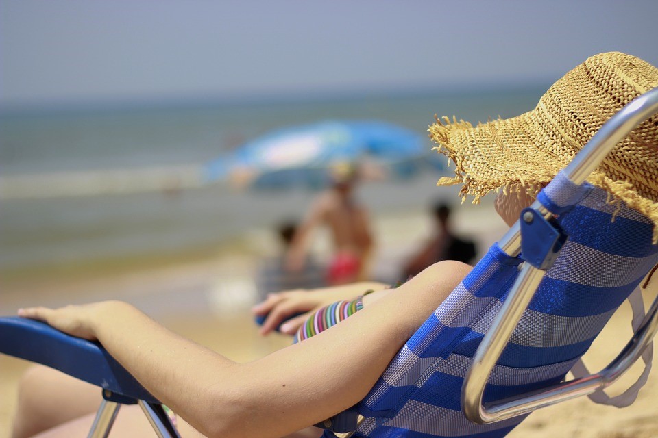 8 Things To Remember When Packing Your Holiday Suitcase laying on beach