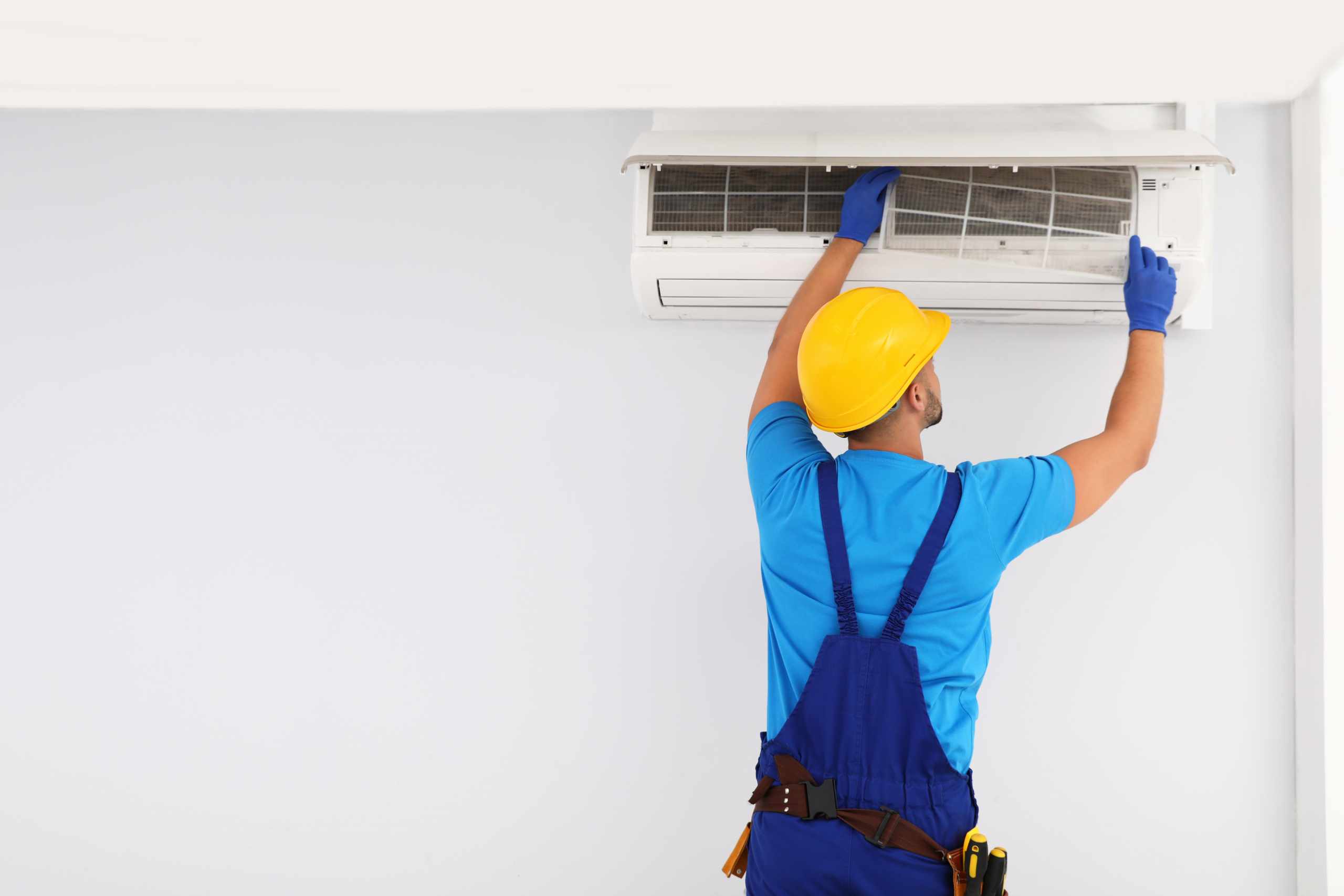 Professional technician maintaining modern air conditioner indoors. Space for text