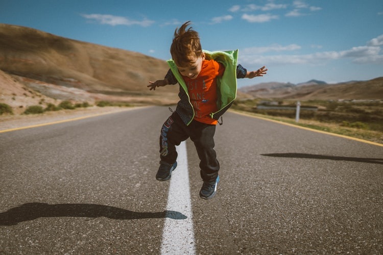 a little boy jumping from joy on a road during a long-distance relocation. 