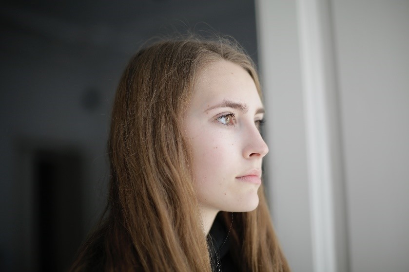 A person with brown hair staring into the distance.